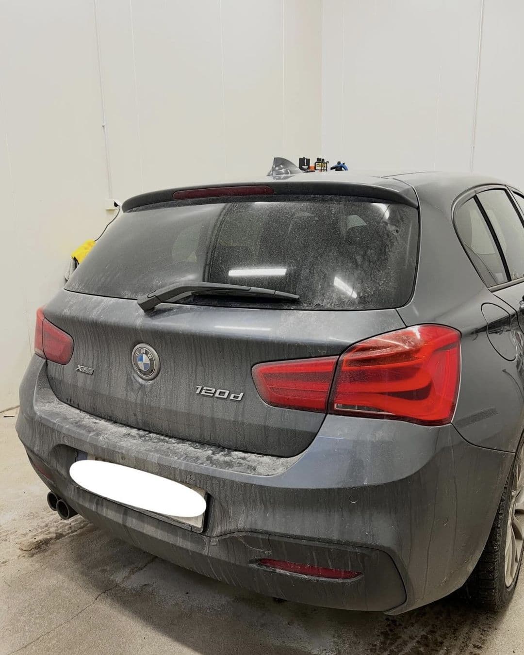 Bakpartiet på en grå BMW 1-serie med smutsig lack före tvätten hos KOM-fort Bilvård i Örebro