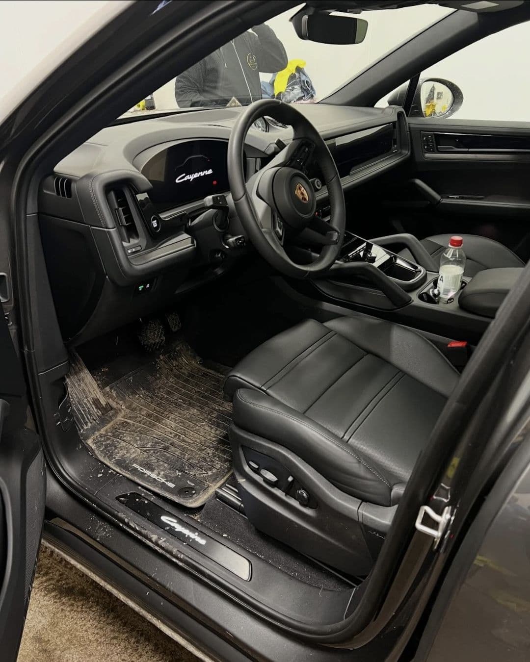 Förarplatsen i en Porsche Cayenne med smutsig golvmatta före rengöringen hos KOM-fort Bilvård i Örebro